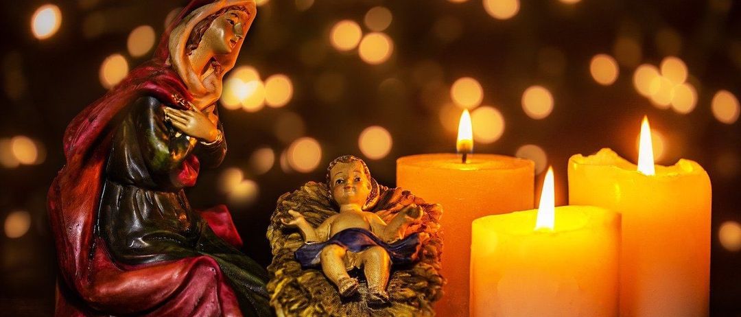 Eine Krippe mit Maria und dem Jesuskind, umgeben von Kerzen und leuchtenden Lichtern.