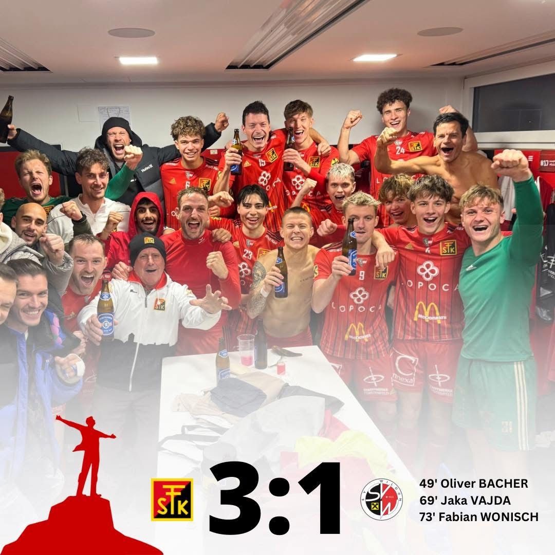 Eine Gruppe von Fußballspielern feiert in einer Umkleidekabine, hält Flaschen in den Händen und trägt rote Trikots. Das Ergebnis 3:1 wird angezeigt. Ein Mann in einer weißen Jacke hält eine Flasche.