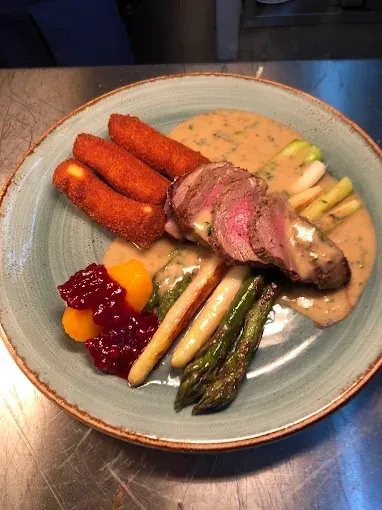 Ein Teller mit einem Steak, Spargel und Cranberry-Sauce.