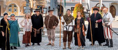 Eine Gruppe von Menschen in mittelalterlichen Kostümen posiert für ein Foto vor historischen Gebäuden.