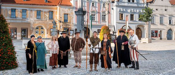 Eine Gruppe von Menschen in mittelalterlichen Kostümen posiert für ein Foto auf einem historischen Stadtplatz.