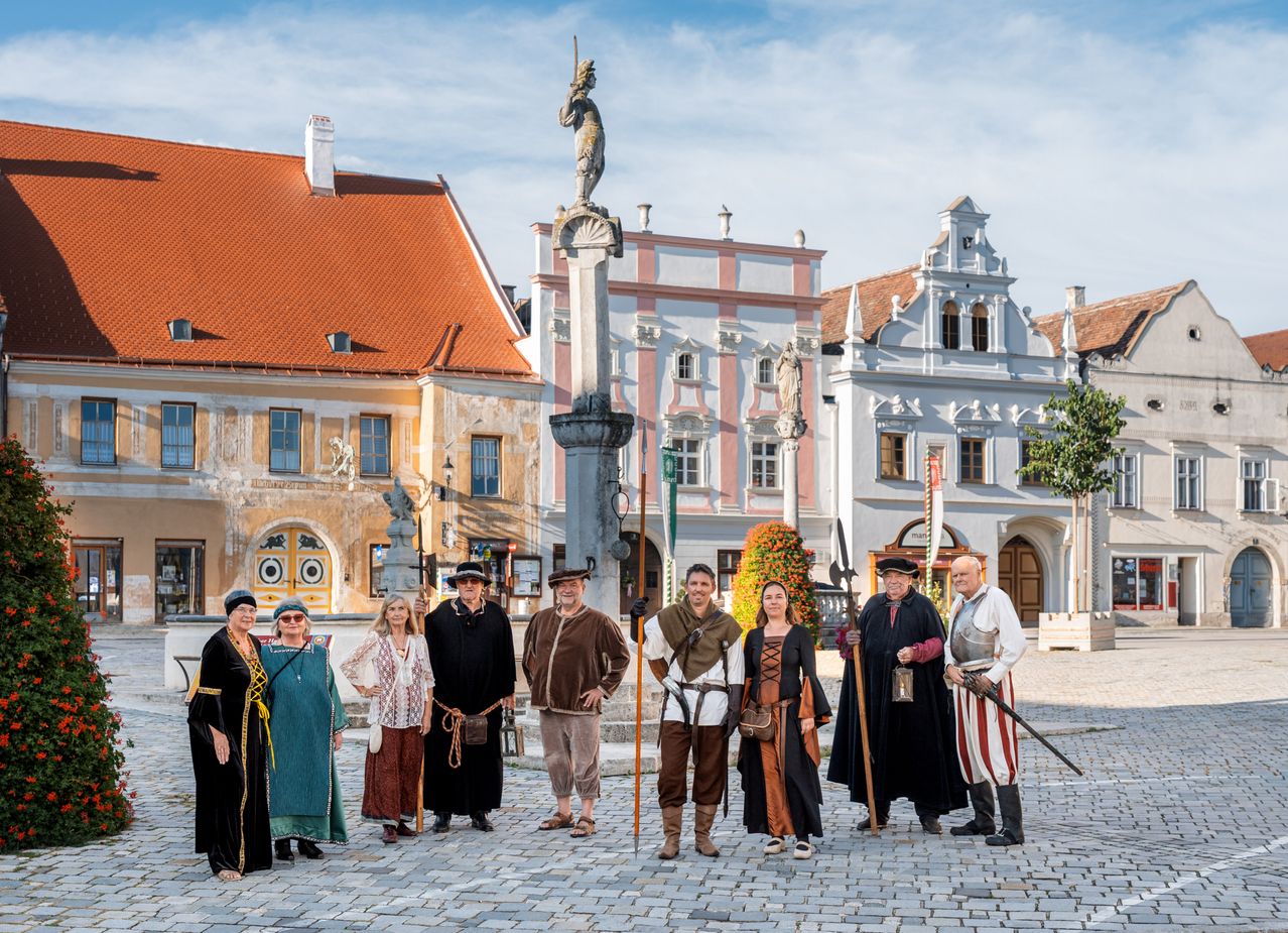 Eine Gruppe von Menschen in mittelalterlichen Kostümen posiert für ein Foto vor historischen Gebäuden.