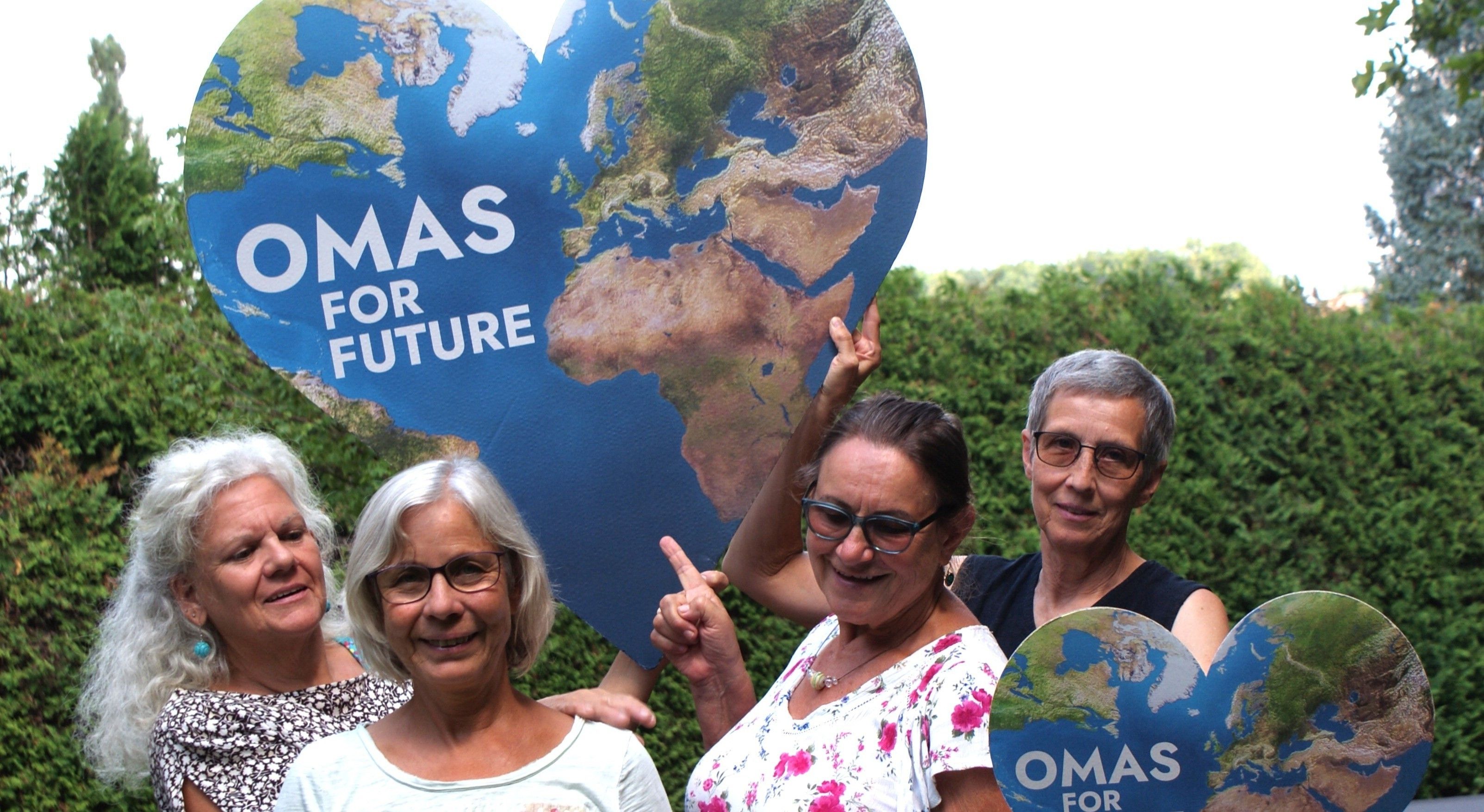 Drei Frauen halten eine Karte der Welt in Herzform mit der Aufschrift 'MAS FOR FUTURE' und posieren für ein Foto.