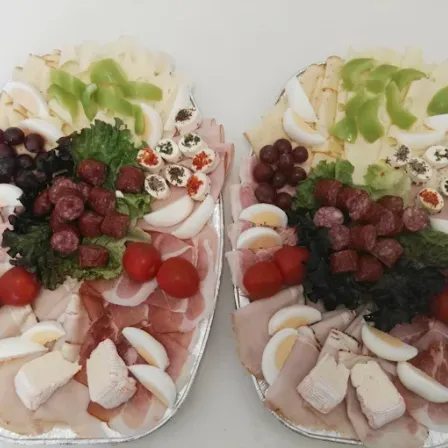 Zwei Tabletts mit einer Vielfalt an Lebensmitteln, einschließlich Eier, Fleisch, Gemüse und Gewürzen.