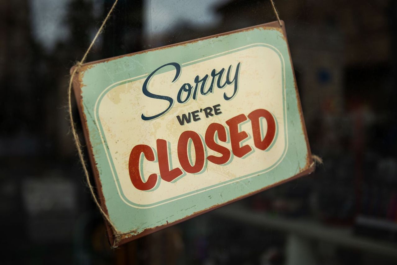 Ein Vintage-Schild mit der Aufschrift 'Sorry, We're Closed' hängt an einer Glastür und verleiht einen rustikalen Look.
