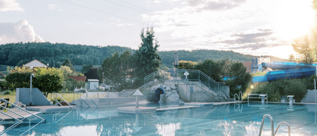 Eröffnungstag in einem familienfreundlichen Freizeitbad mit Pool, Rutschen und einer schönen Landschaft im Hintergrund.