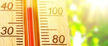 Ein Thermometer mit einer roten Linie, die die Temperatur bei 30 Grad Celsius anzeigt, mit einem unscharfen grünen Hintergrund.