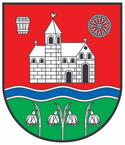 Ein heraldisches Wappenschild mit einer Kirche, einem Kirchturm, einem Rad darüber und Lilien darunter auf rotem Hintergrund.
