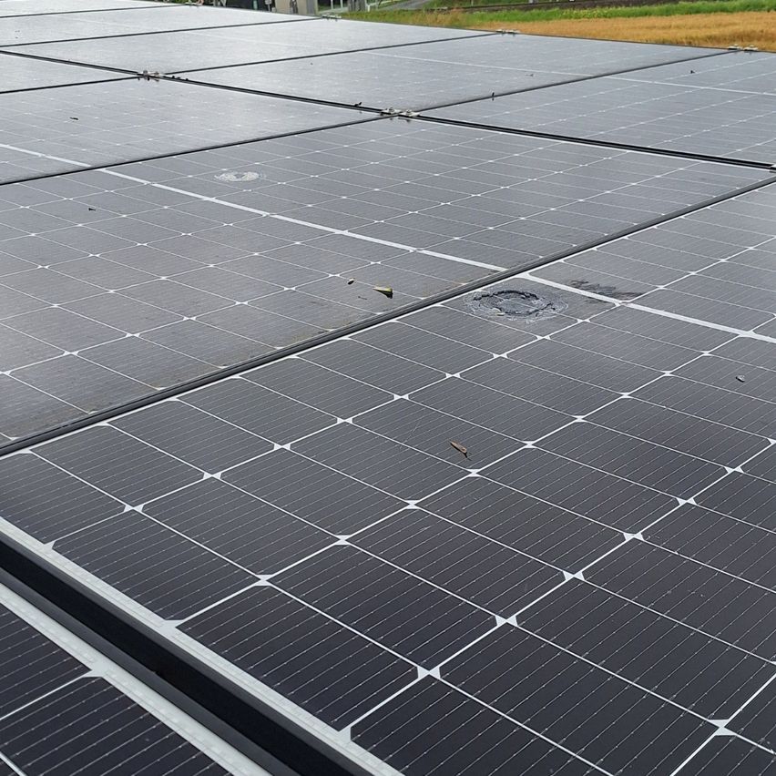 Eine Anordnung von Solarmodulen mit mehreren Modulen in Reihen und Spalten. Einige Module weisen sichtbare Schäden auf, einschließlich Risse und Löcher. Die Module sind auf einem Metallrahmen montiert.