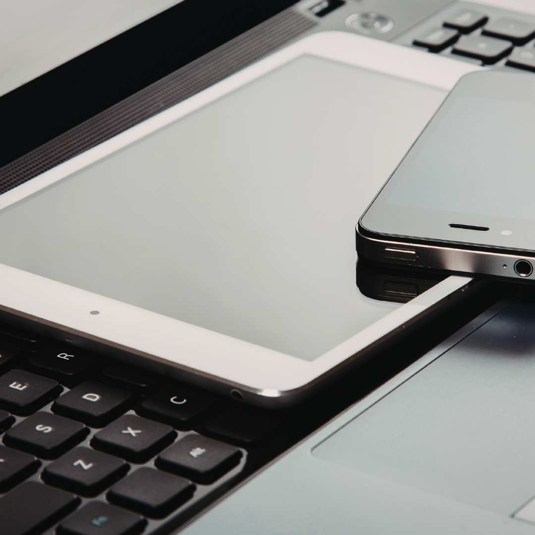 Ein Laptop und ein Smartphone liegen auf einem Tisch. Der Laptop hat eine Tastatur, und das Smartphone ist mit dem Laptop verbunden. Der Bildschirm des Laptops ist ausgeschaltet.