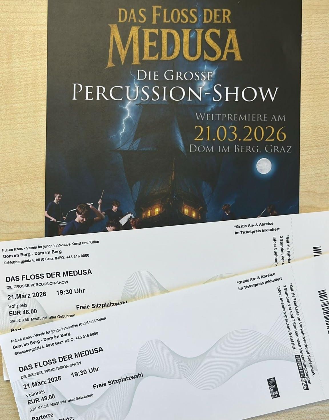 Poster und Tickets für Medusa Percussion Show, Weltpremiere am 21.03.2026 in Graz. Das Poster zeigt ein Schiff mit Blitz und Mond. Die Tickets haben Text auf Deutsch und Englisch, einschließlich Preise und Termine.