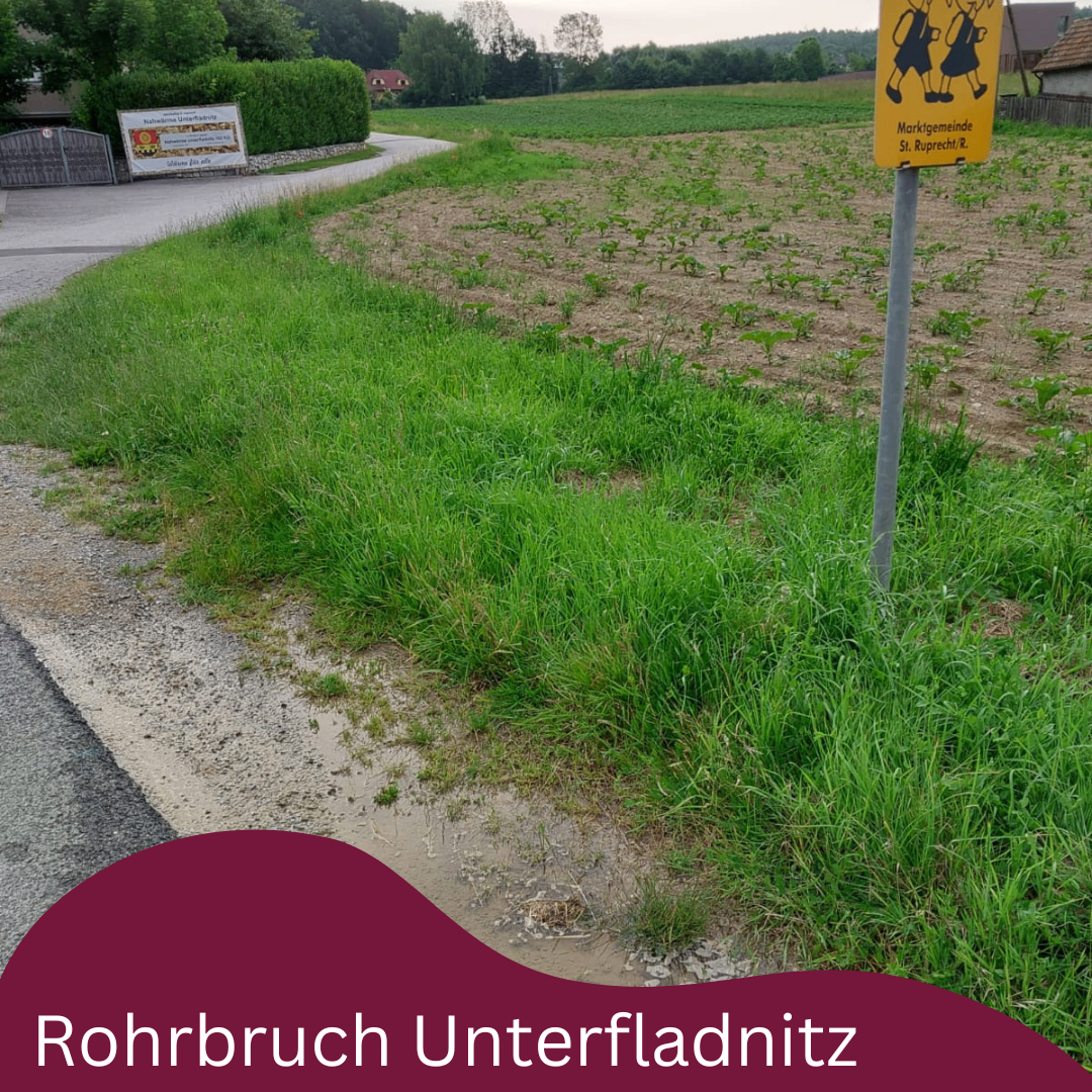 Ein Bild einer grasigen Fläche mit einem Schild, das 'Marktgemeindende St. Ruprecht/R.' steht, mit einem Weg, der zu einem Ackerfeld führt.