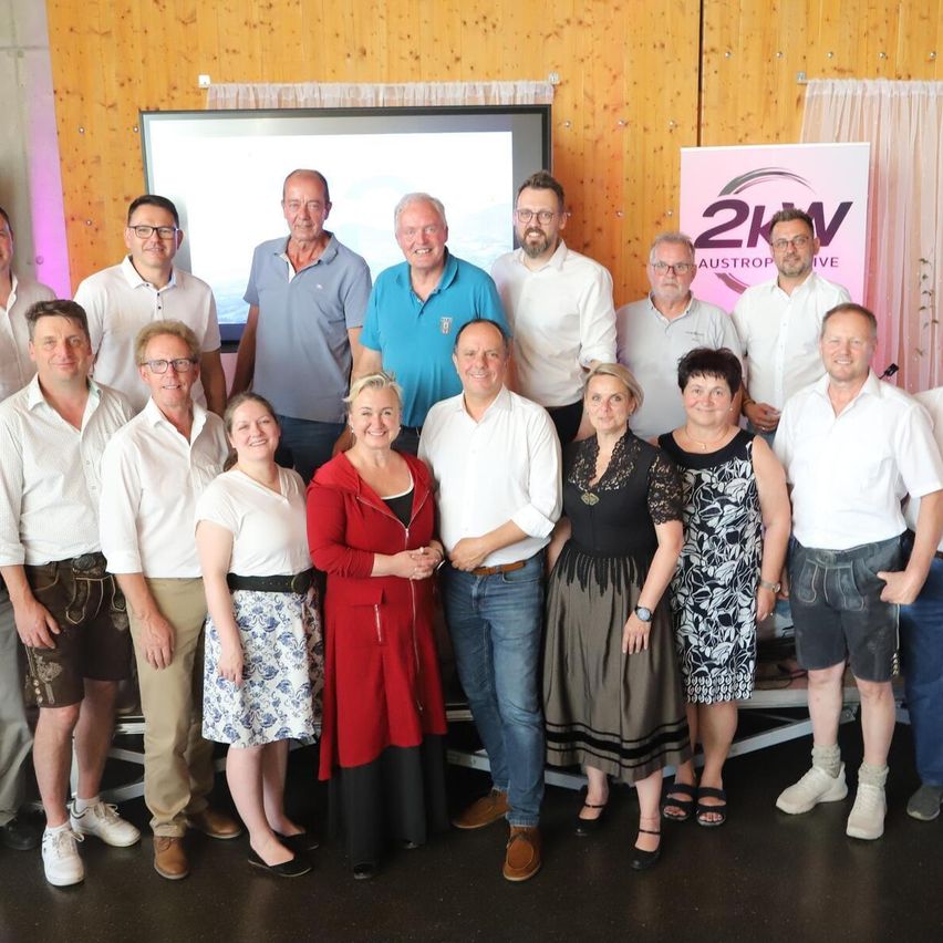 Eine Gruppe von Menschen in Freizeitkleidung, die für ein Foto vor einer Holzwand stehen.