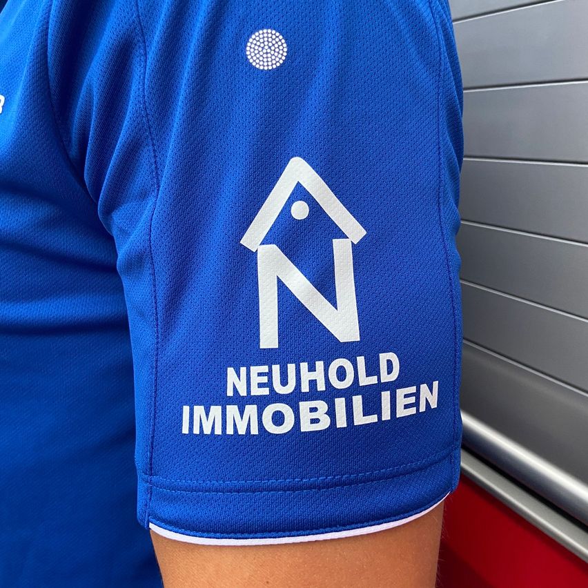 Ein blaues Trikot mit einem weißen Logo, das ein Haus und die Buchstaben N zeigt, und wirbt für Neuhold Immobilien.