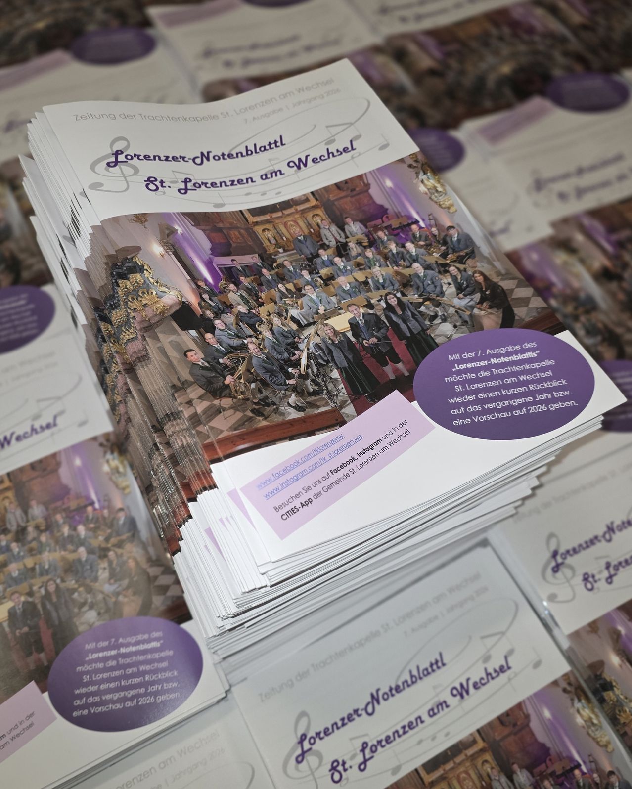 Ein Stapel Broschüren für St. Lorenzen am Wechsel, mit einem Bild einer Musikgruppe, und Text über ein bevorstehendes Ereignis.