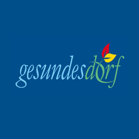 Blauer Hintergrund mit 'Gesundes Dorf' in kursiver grüner und blauer Schrift, mit einem roten und gelben Blattsymbol.