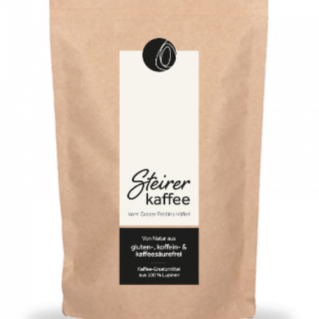 Braune Papiertüte mit weißem Etikett, das den Markennamen 'Steirer kaffee' zeigt. Das Etikett enthält das Logo der Marke und Informationen darüber, dass das Produkt gluten-, koffein- und kaffeesäurefrei ist.