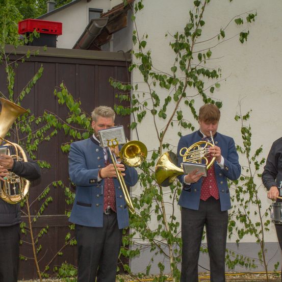 Vier Musiker spielen vor einem Gebäude und spielen jeweils ein Blechblasinstrument. Zwei spielen Posaunen, einer spielt eine französische Horn und der vierte spielt eine Tuba.