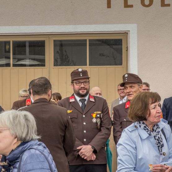 Eine Gruppe von Personen in Militäruniformen steht vor einem Gebäude. Sie scheinen in ein Gespräch vertieft zu sein.