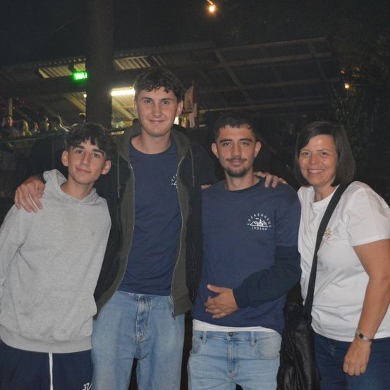 Vier Personen posieren nachts für ein Foto. Zwei Jungen tragen Freizeitkleidung, und zwei Männer tragen blaue Hemden. Eine Frau lächelt und steht neben ihnen.