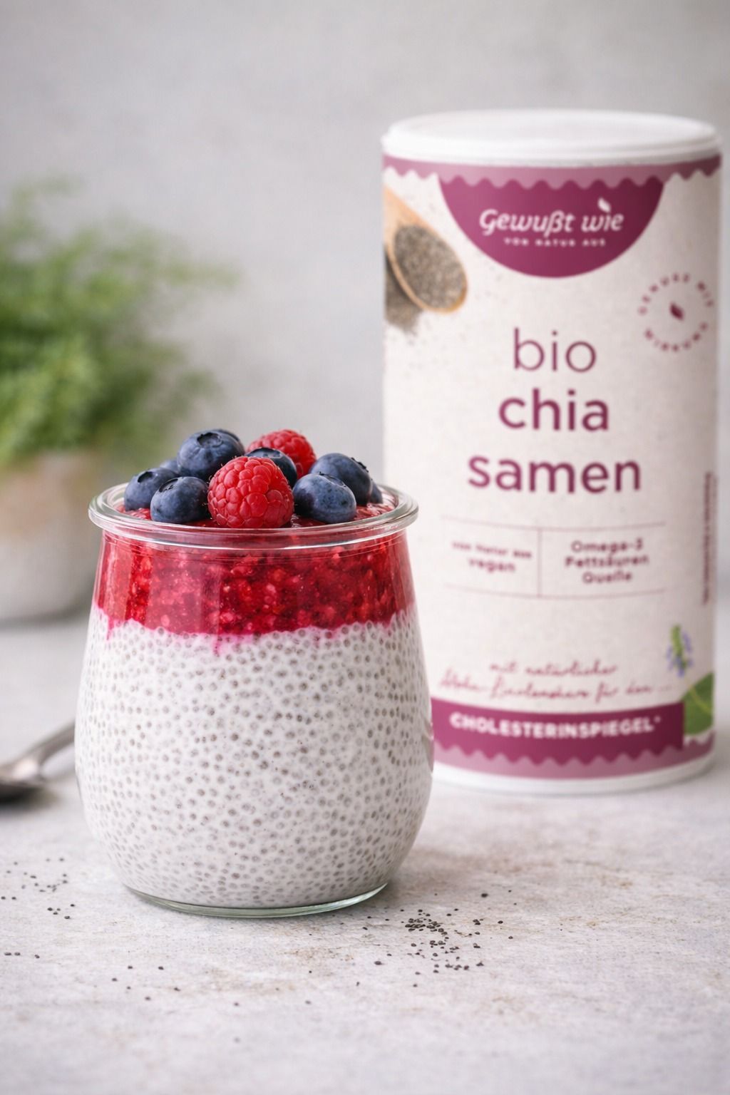 Chiasamen mit Beeren und Joghurt in einem Glas, ein Glas Chiasamen im Hintergrund.