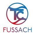 Das Logo von Fussach zeigt einen stilisierten Buchstaben T mit einem Wellendesign in einem Kreis, über dem Wort Fussach in fetter blauer Schrift.