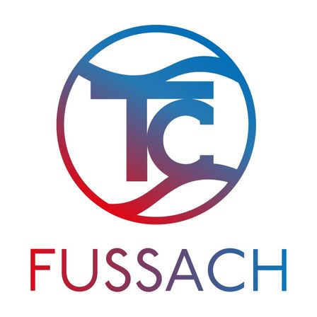 Das Logo von Fussach zeigt einen stilisierten Buchstaben T mit einem Wellendesign in einem Kreis, über dem Wort Fussach in fetter blauer Schrift.