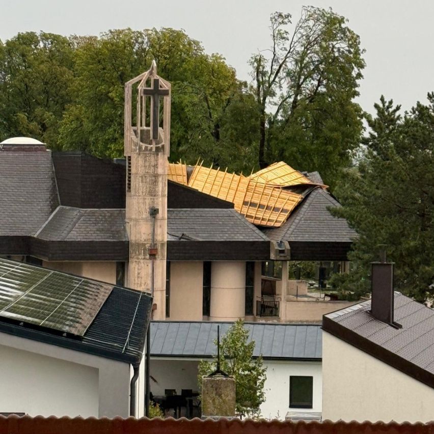 Eine Kirche mit beschädigtem Dach, einem Kreuz auf einem Turm und Solarpanelen an der Seite.