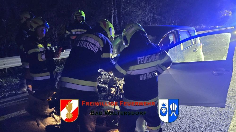 Freiwillige Feuerwehr Bad Waltersdorf kümmert sich bei Nacht um einen Autounfall, mehrere Einsatzkräfte sind um das beschädigte Fahrzeug beschäftigt.