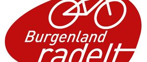 Das Burgenland radelt Logo zeigt einen roten Oval mit einem weißen Fahrrad darin, die Worte 'Burgenland radelt' sind in weißer Schrift darunter geschrieben.