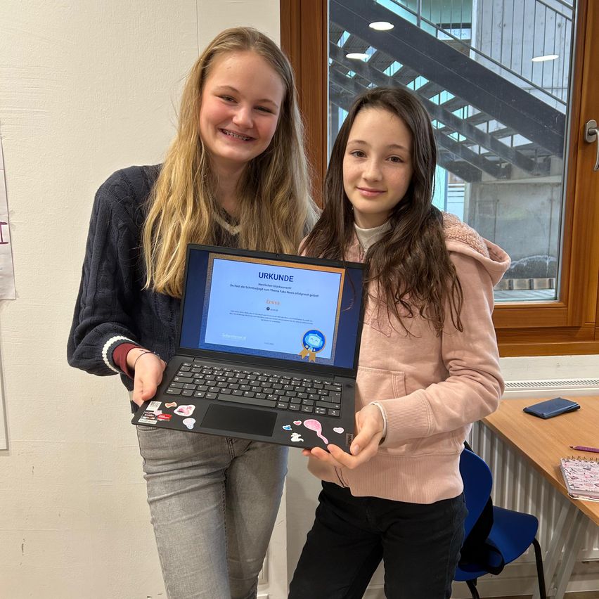 Bild enthält, Furniture, Table, Desk, Pants, Person, Computer, Laptop, Face, Jeans, Coat