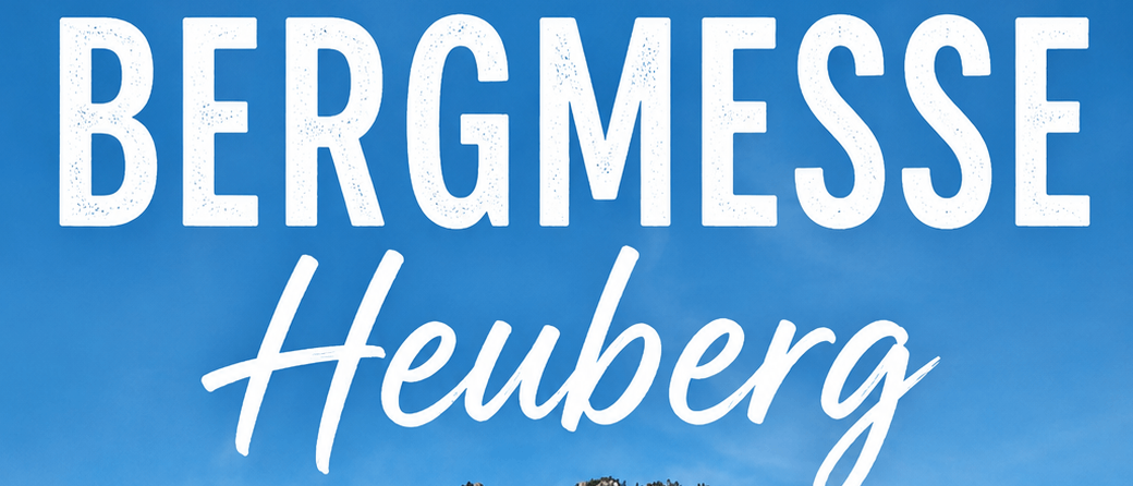 Eine landschaftliche Aufnahme eines Berges mit einem Kreuz auf der Spitze, umgeben von einem üppigen grünen Feld und einem Haus im Vordergrund. Das Bild hat einen Wasserzeichen mit dem Text 'BERGMESSE Heuberg'.