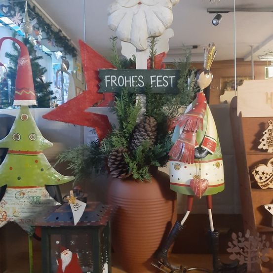 Eine Weihnachtsdekoration mit einem Schild Frohes Fest, einem Weihnachtsbaum und Weihnachtsmannfiguren.