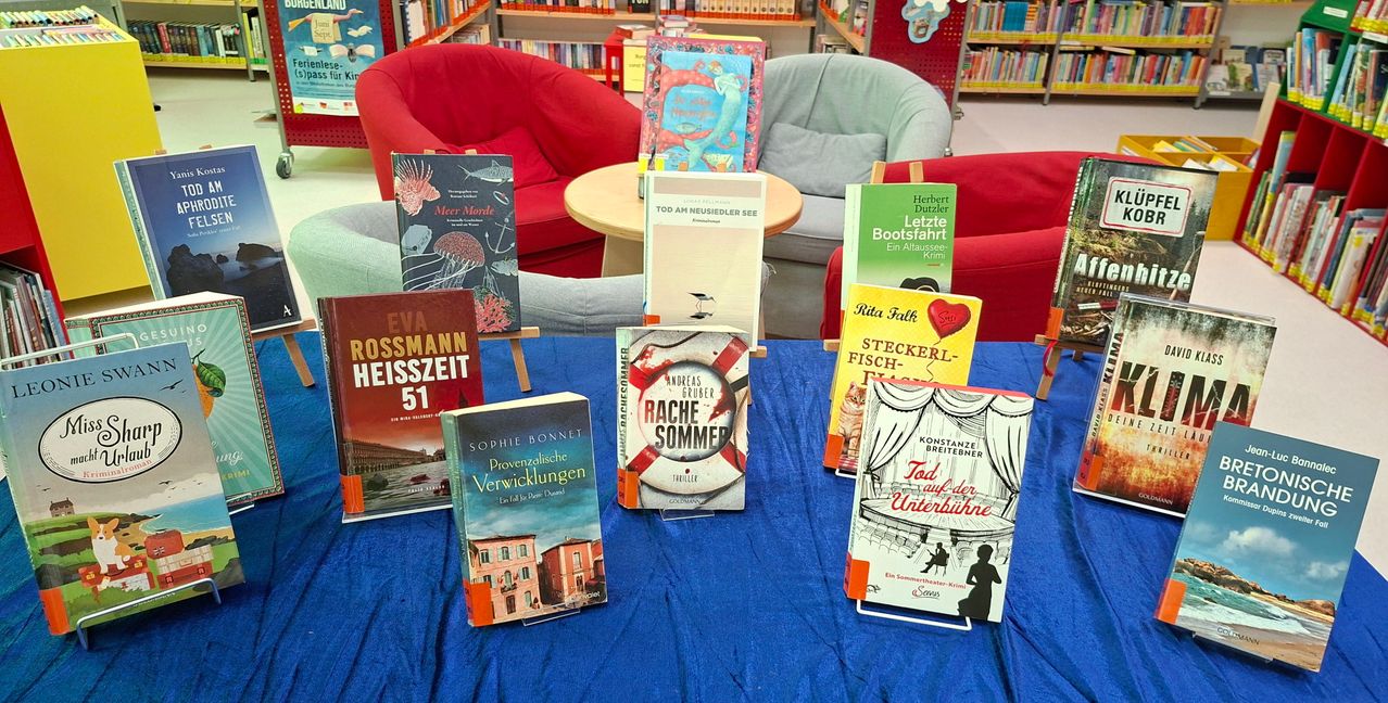 A collection of books are displayed on a blue table. The books have titles such as Eva Rossmann, Sophie Bonnet, and Tod auf der Unterbühne.
