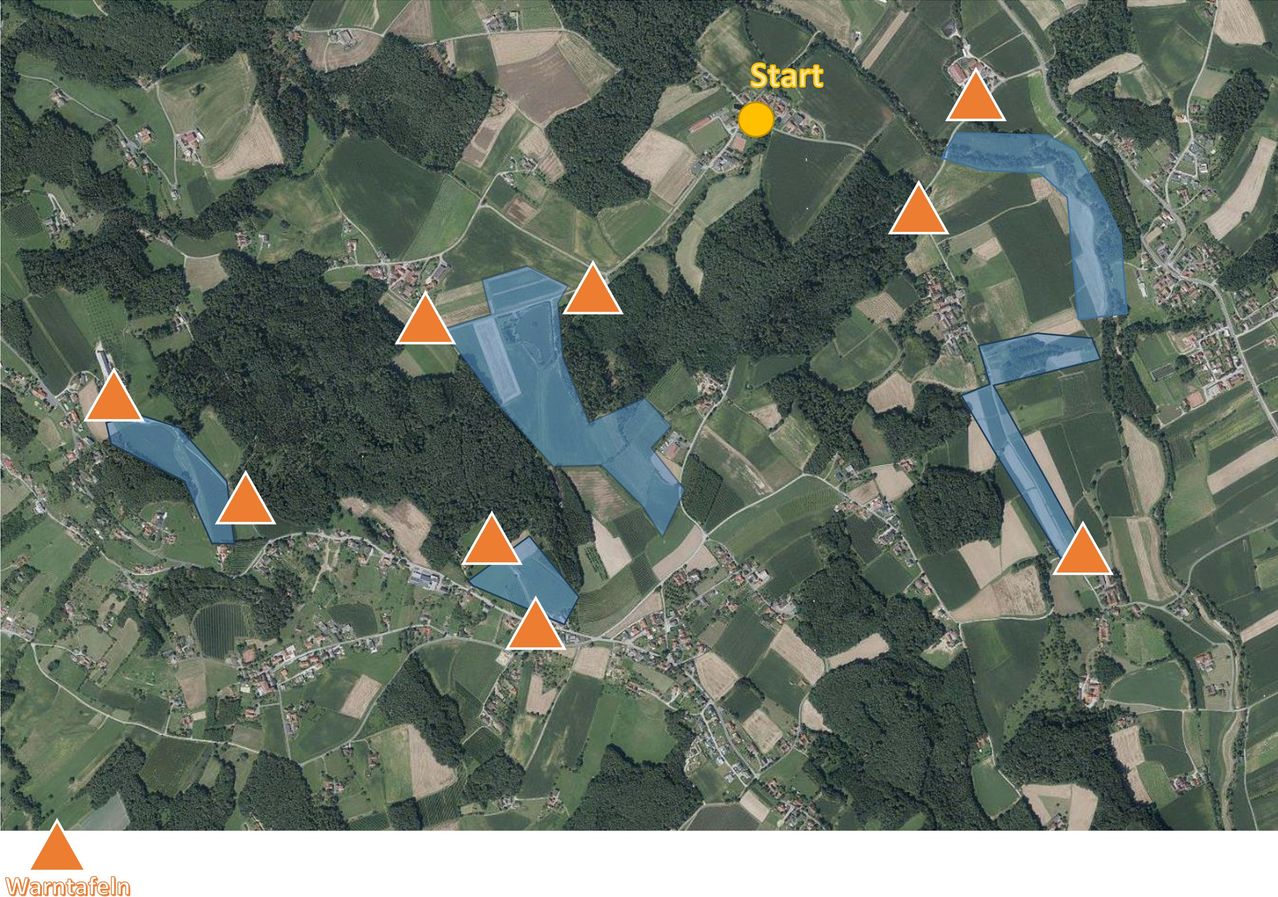 Luftaufnahme eines ländlichen Gebiets mit Start in Gelb markiert und mehreren orangefarbenen Dreiecken, die Punkte von Interesse anzeigen. Die Landschaft besteht aus einer Mischung aus grünen Feldern und blauen Gewässern.
