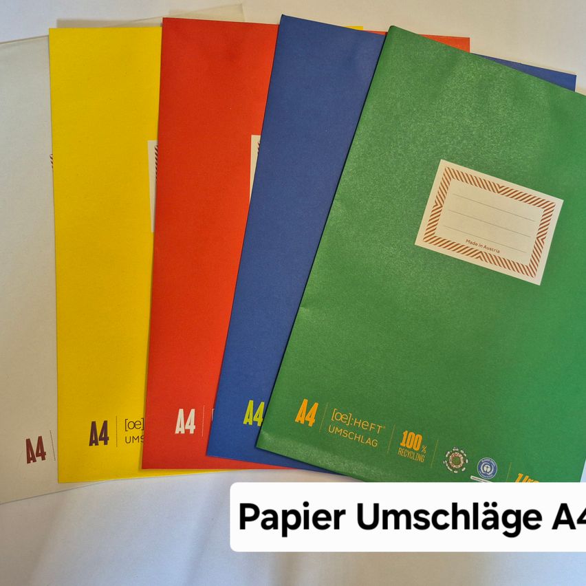 Stapel bunter Papiermappen mit der Aufschrift A4, wobei eine Mappe ein weißes Etikett mit der Aufschrift 'Made in Austria' und '100% Recycling' trägt.