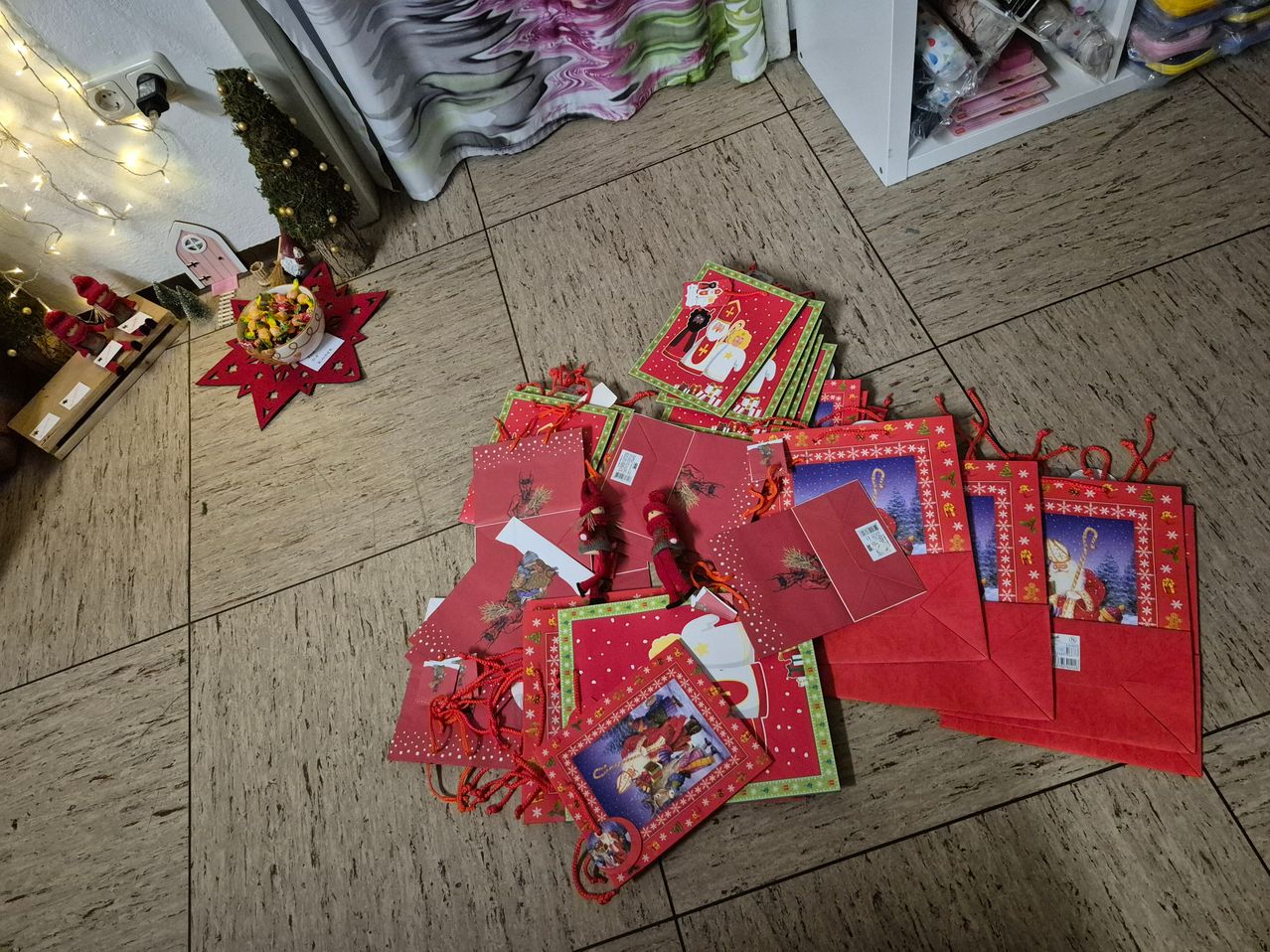 Ein Boden ist mit mehreren roten Geschenktüten bedeckt, einige offen, andere geschlossen, mit verstreuten Weihnachtsdekorationen.