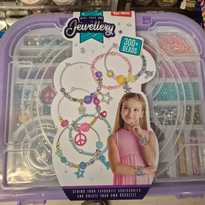 Ein lila Schmuckherstellungsset enthält ein Bild eines Mädchens und verschiedene Armbänder mit Friedenszeichen, Stern und anderen Dekorationen. Es enthält 300+ Perlen und Werkzeuge zum Erstellen von Armbändern.