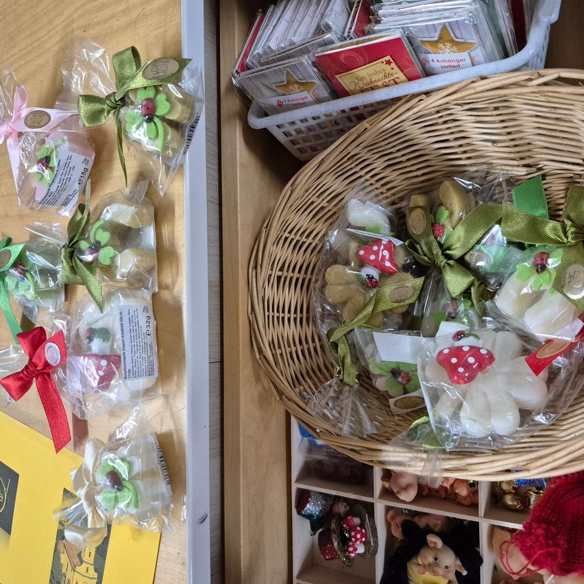 Auf einem Holztisch stehen zwei Körbe mit verpackten Süßigkeiten. Ein Korb hat Bonbons mit Schleifen, während der andere Bonbons mit grünen Schleifen enthält.