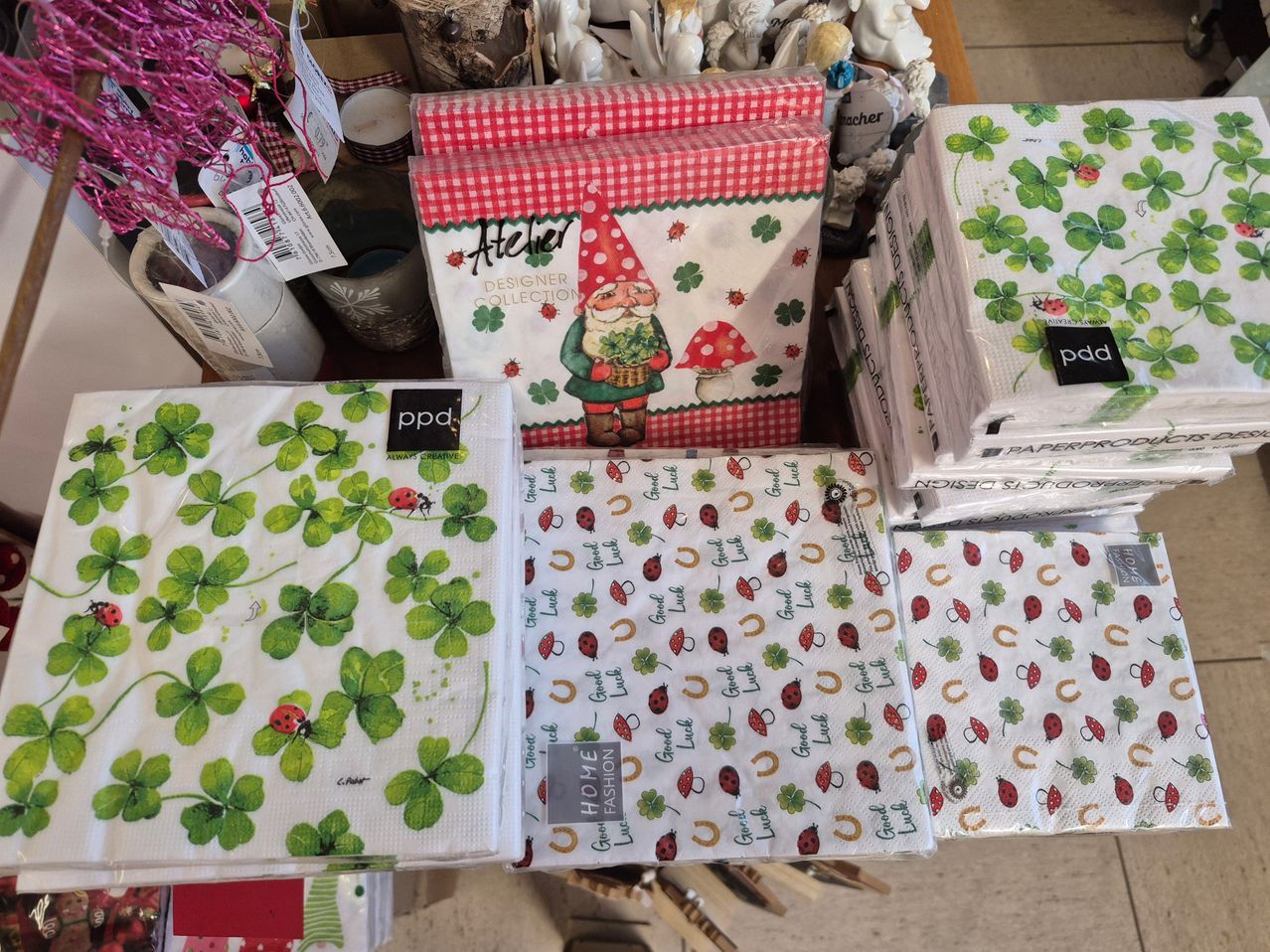 Eine Sammlung von Servietten mit verschiedenen Designs, darunter ein Gnom, Marienkäfer, Kleeblätter und Hufeisen, auf einem Holztisch ausgestellt.