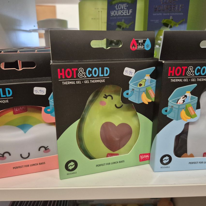 Ein Regal mit mehreren Schachteln wiederverwendbarer thermischer Gelpacks, darunter solche in Form einer Avocado und eines Lunchbox, alle mit der Marke Hot&Cold gekennzeichnet.