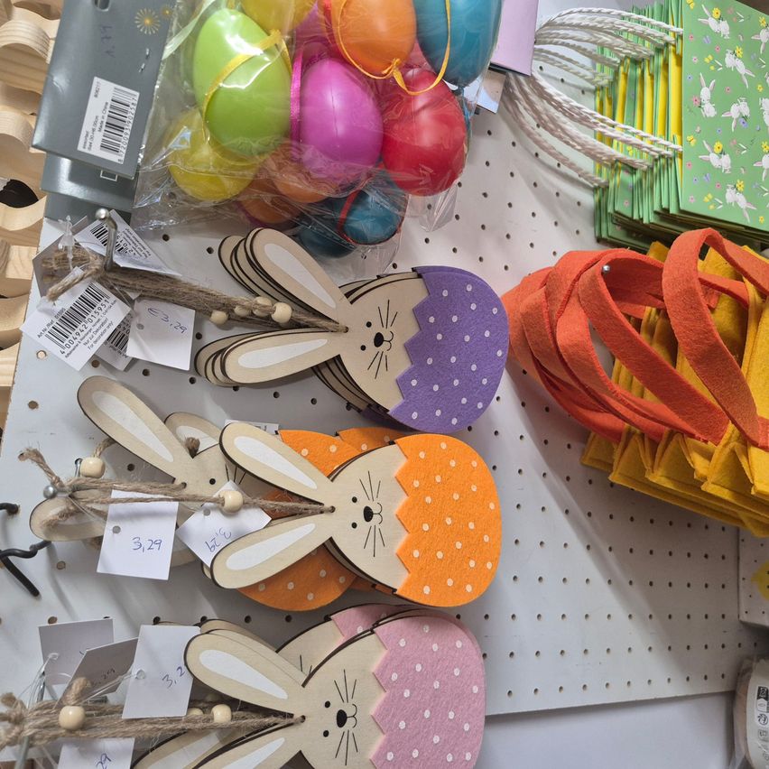 Eine Ausstellung von Osterdekorationen umfasst verschiedene Filzhasen in Eierformen, bunte Eier in Plastik und orange Filtbänder.
