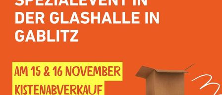 An orange poster advertises a special event in the glass hall in Gablitz. The event is scheduled for November 15th and 16th. It features a stack of brown cardboard boxes on the right side. The text is written in white and yellow fonts.