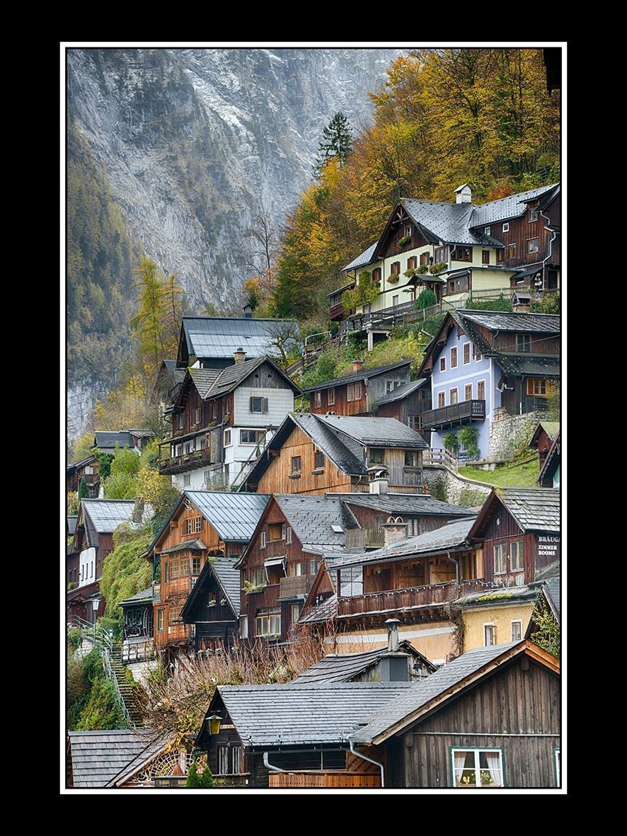 A village with charming wooden houses nestled in a valley surrounded by trees and mountains.