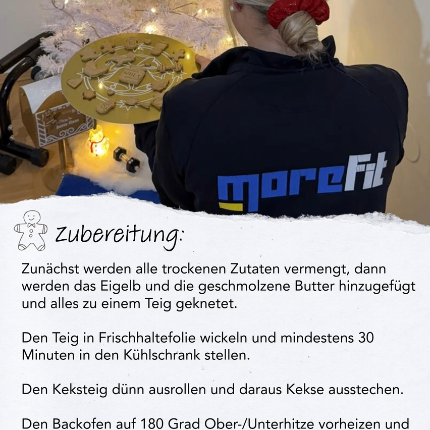 Eine Frau in einem moreFit-Shirt bereitet Lebkuchen auf einer festlichen Einrichtung vor, mit einem Weihnachtsbaum und einem Lebkuchenhaus im Hintergrund. Anleitungen auf dem Bild führen durch den Lebkuchen-Herstellungsprozess.
