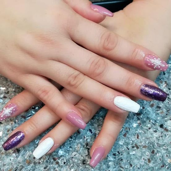 Ein Nahaufnahme der Hände einer Person mit winterlichem Nagellack auf einer glitzernden Oberfläche.