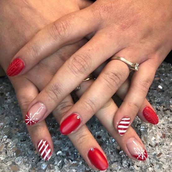 Ein Nahaufnahme von Händen mit roten und weißen gestreiften Nägeln, eine Hand hat einen Diamantring und die andere einen Ring am Mittelfinger.