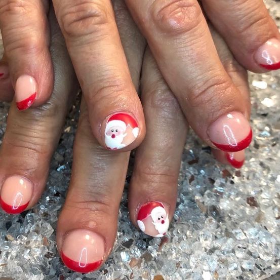 Nahaufnahme von lackierten Nägeln mit Weihnachtsmann-Designs. Die Nägel sind in einem roten und weißen Farbschema lackiert, mit einer kristallartigen Oberfläche.