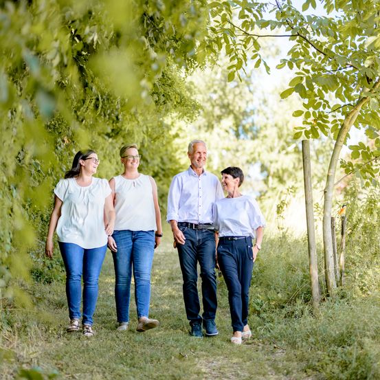 Vier Menschen laufen auf einem Grasweg im Wald. Sie tragen alle Freizeitkleidung.