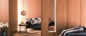 Ein modernes Wohnzimmer mit einem blauen Sofa, gemusterten Tapeten und einer dekorativen Lampe, die an der Decke hängt. Ein Tisch mit Büchern und einem goldenen Objekt befindet sich in der Nähe.